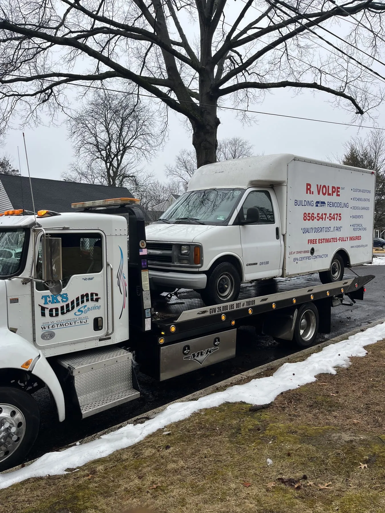 A contractor's box van loaded on the TK's Towing flatbed in the snow