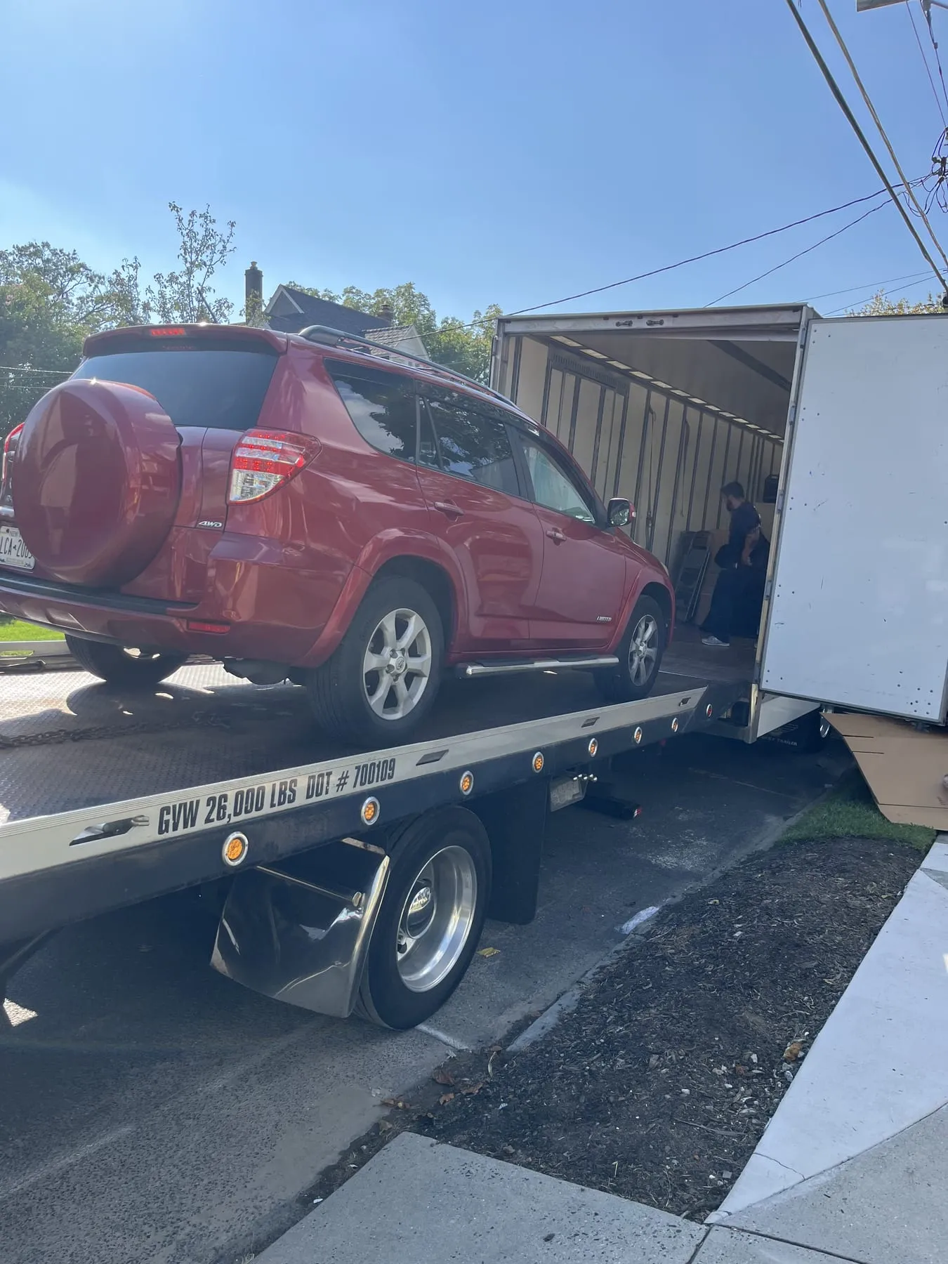 A red Toyota RAV4 loaded on the TK's Towing flatbed on a residential street