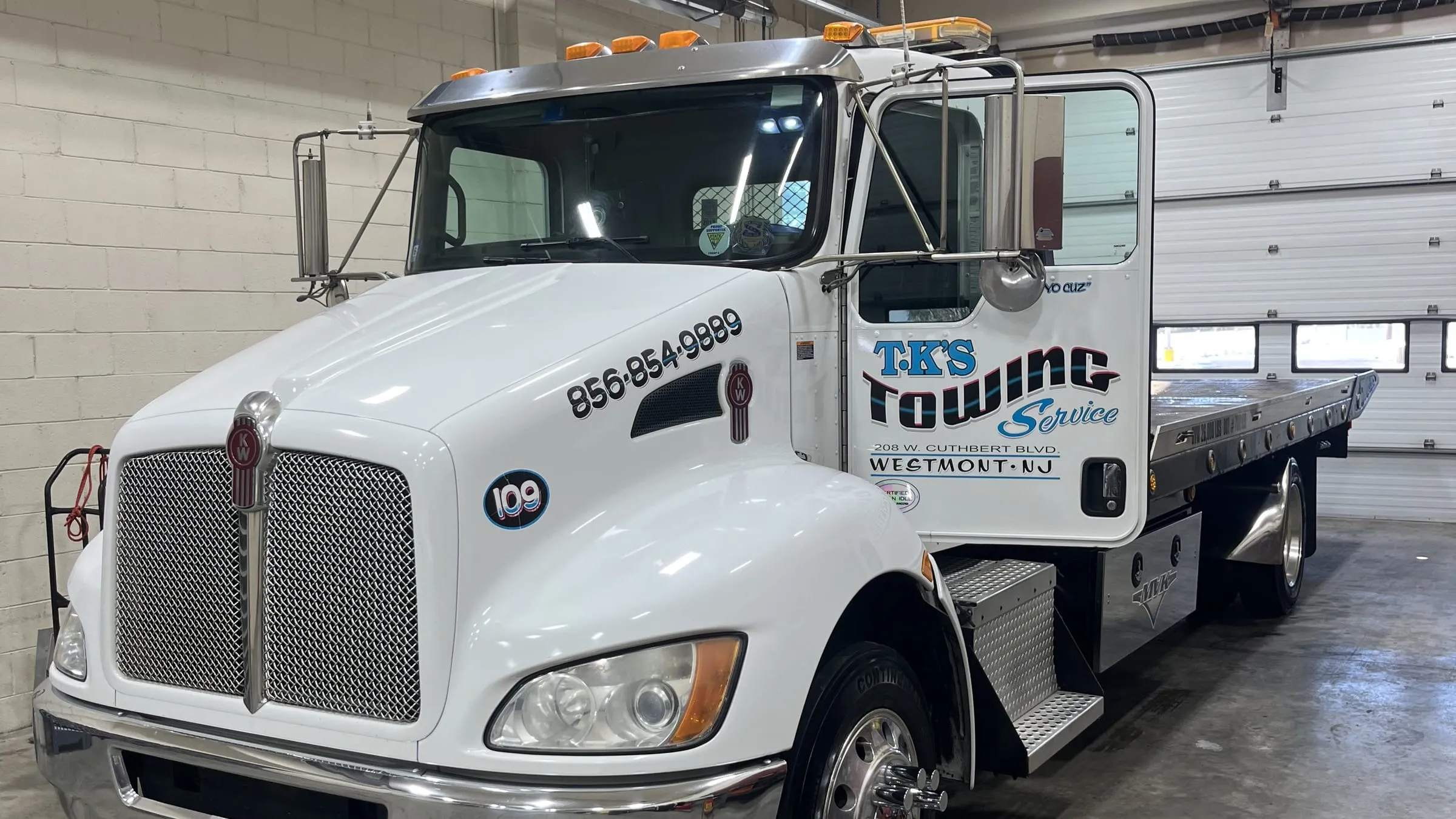 TK's Towing flatbed truck, cab and empty deck, parked in the garage