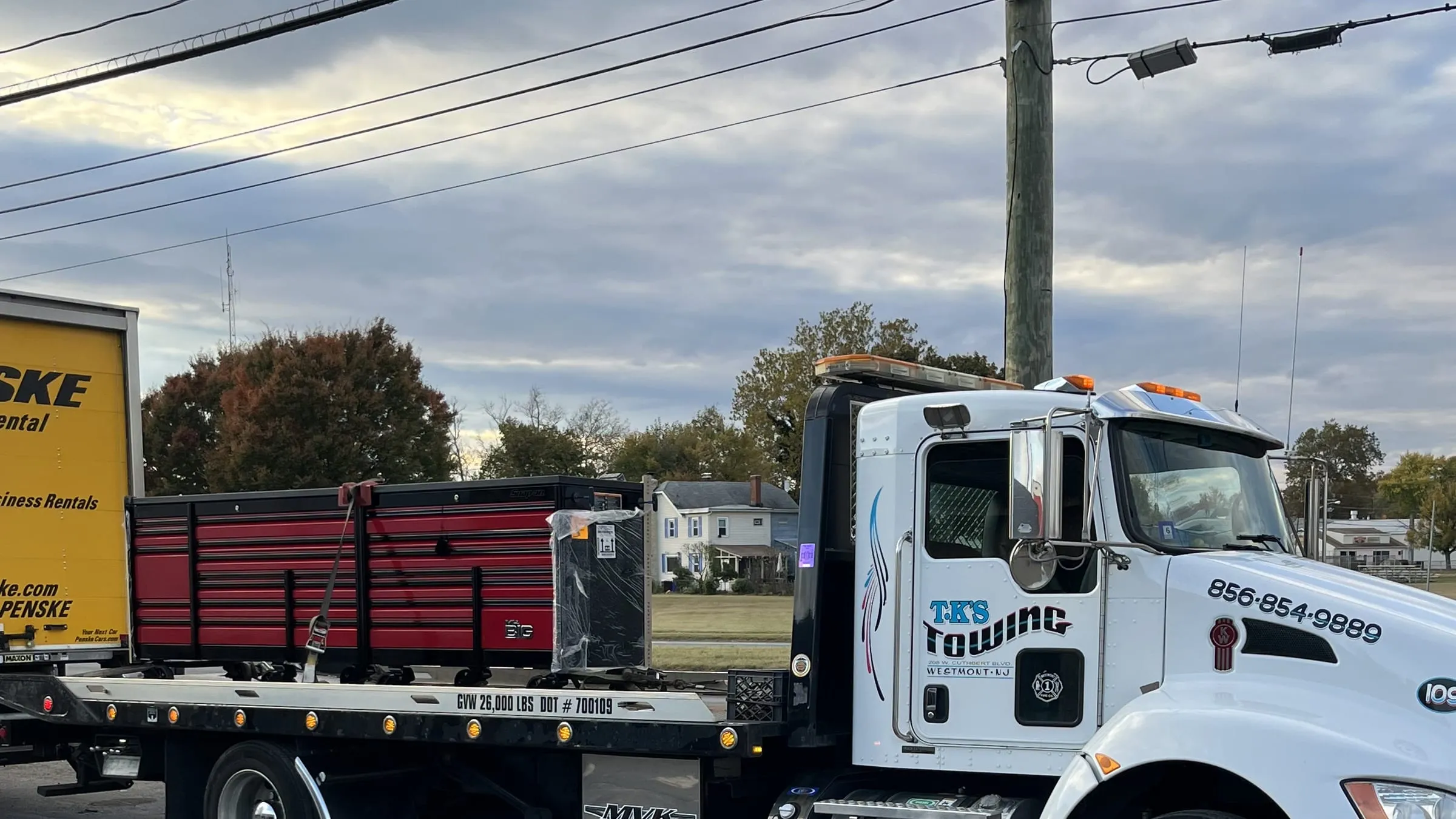 The TK's Towing flatbed loaded and on the road at dusk